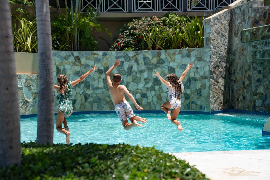 three kids jumping into resort pool